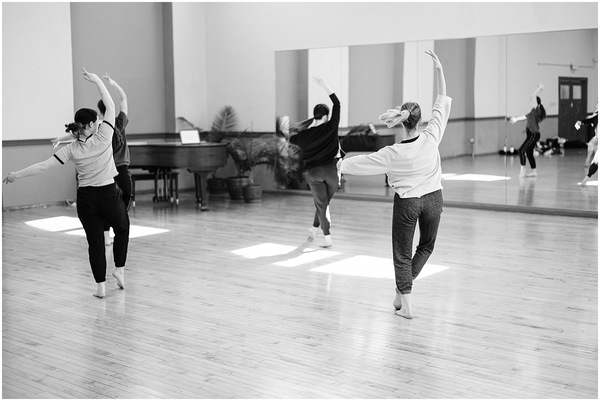 Three contemporary dancers practicing together in a sunlit United States studio